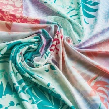 Colorful, lightweight fabric with a tropical floral pattern, gently draped in soft folds, suitable for summer clothing.