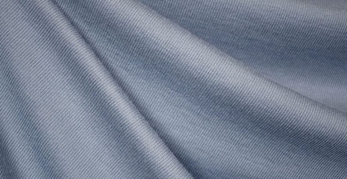 Close-up image of light blue double-knit polyester fabric with a fine, smooth texture and subtle diagonal ribbing.