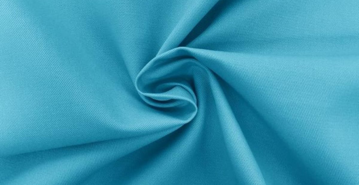 A close-up image of smooth, light blue polyester fabric gently twisted, showcasing its texture and lightweight nature.