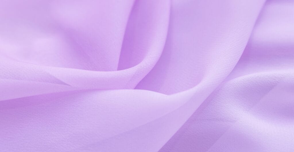 Close-up of soft, light lavender lightweight cotton fabric with gentle folds and a smooth texture.