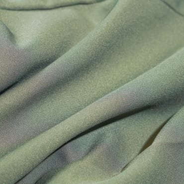 Close-up of light green polyester fabric with a smooth texture, showing gentle folds.