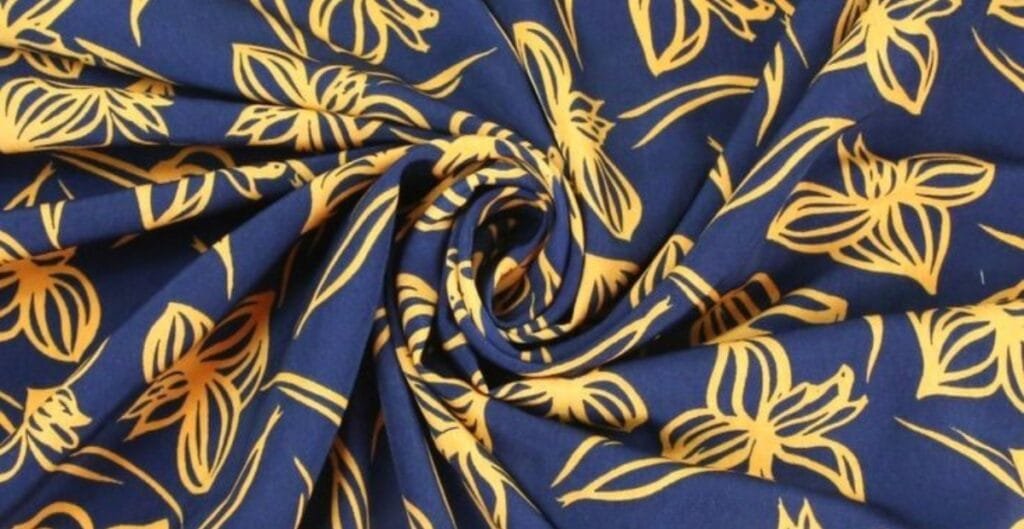 Close-up of blue polyester fabric with a yellow floral print design, arranged in a spiral pattern.