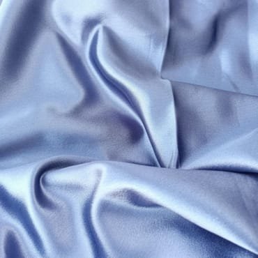 Shiny, smooth, light blue silk polyester blend fabric draped in soft folds, exhibiting a lustrous appearance.