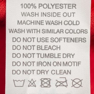 Clothing care label for 100% polyester fabric with washing and drying instructions, including symbols for machine wash, bleaching, drying, ironing, and dry cleaning.