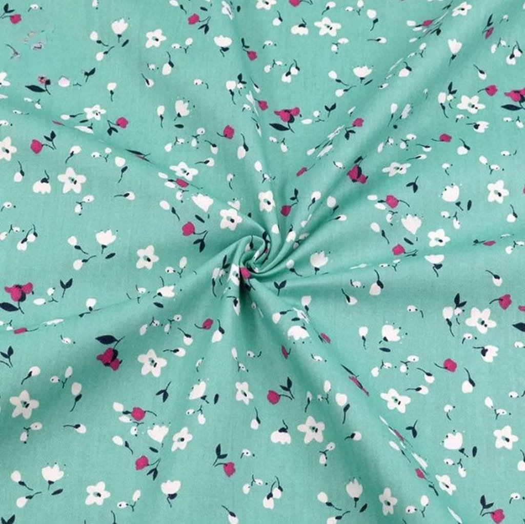 A close-up image of a soft, lightweight cotton lawn fabric featuring a mint green background with small, scattered floral prints in white, pink, and dark green.