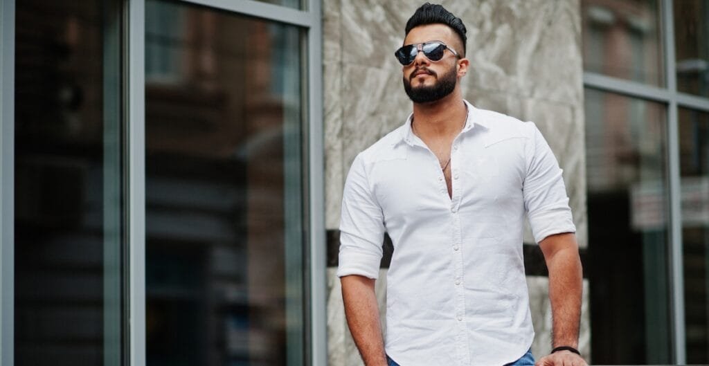 Man wearing a white, breathable summer shirt, standing outdoors near a modern building with large windows and stone accents.