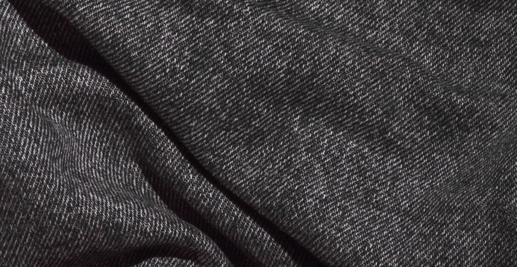 Close-up image of black denim fabric with a fine diagonal weave pattern.