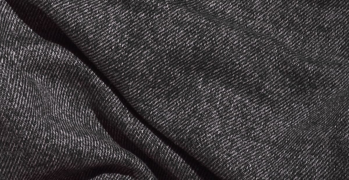 Close-up image of black denim fabric with a fine diagonal weave pattern.