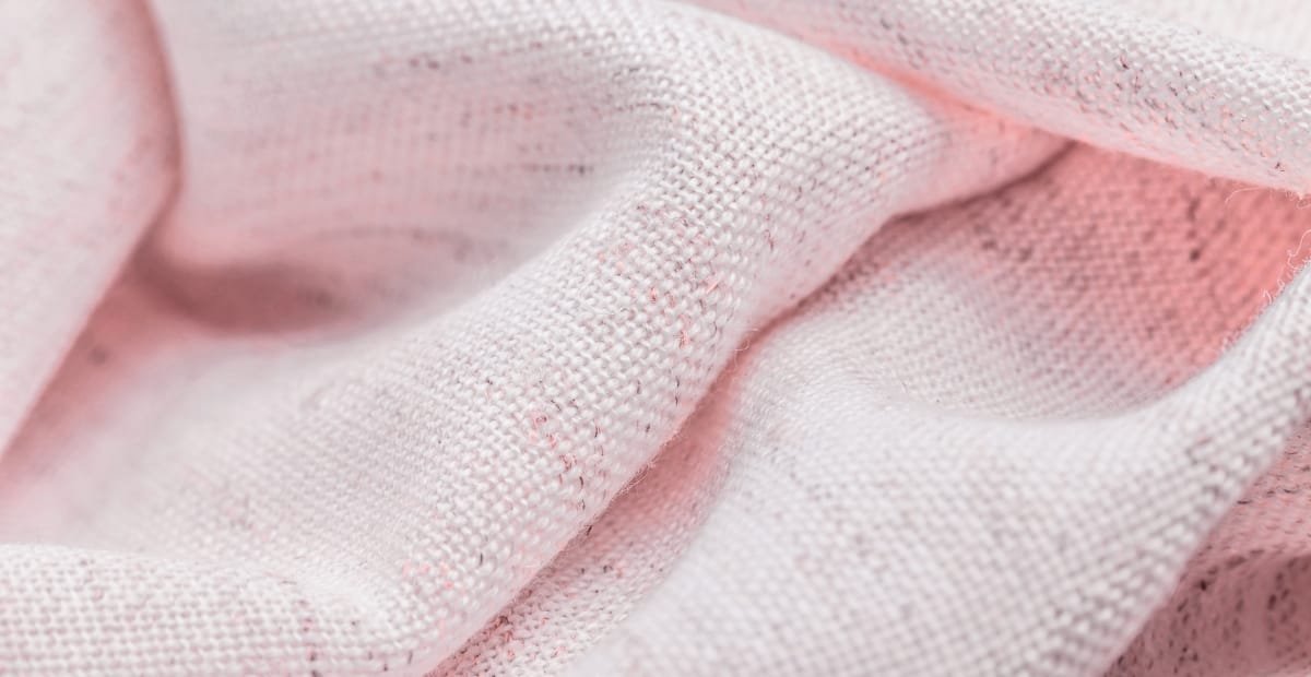 Close-up image of coarse, lightly textured pink cotton fabric with visible weave and fibers