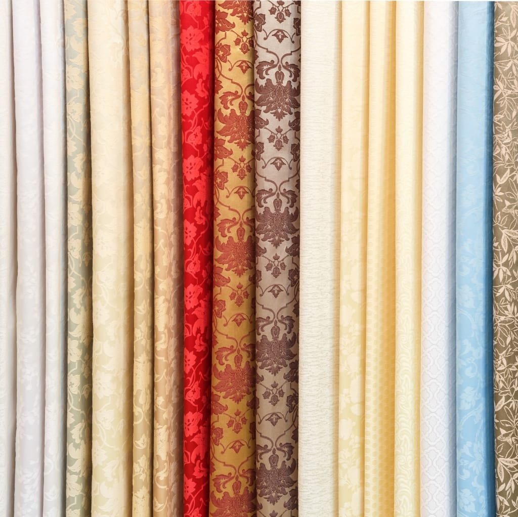 A collection of cotton fabrics with various colors and patterns, showcasing a satin weave texture.