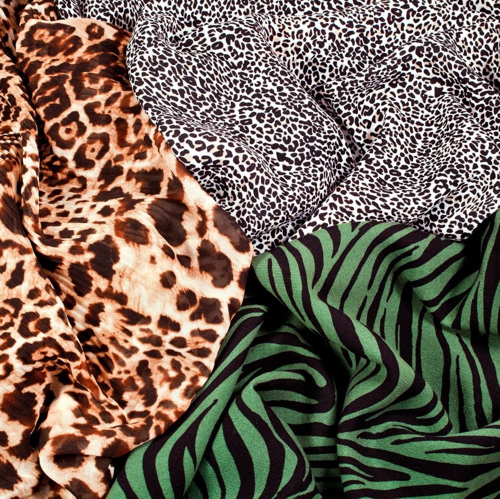 Close-up image of vibrant printed fabrics with animal patterns, including leopard, cheetah, zebra prints in various colors.