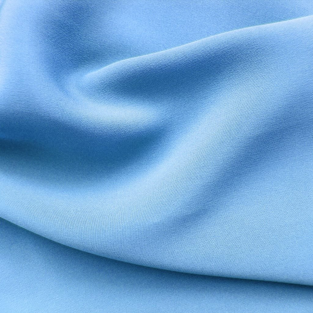 Close-up of smooth, light blue fabric with a soft, matte finish and gentle folds.