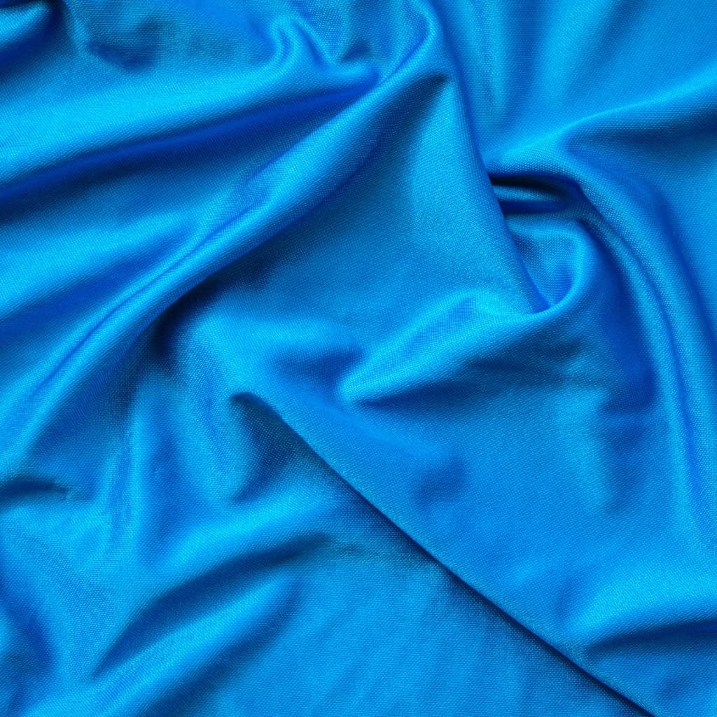 Close-up photograph of shiny, smooth, bright blue nylon spandex fabric with gentle folds and subtle sheen.