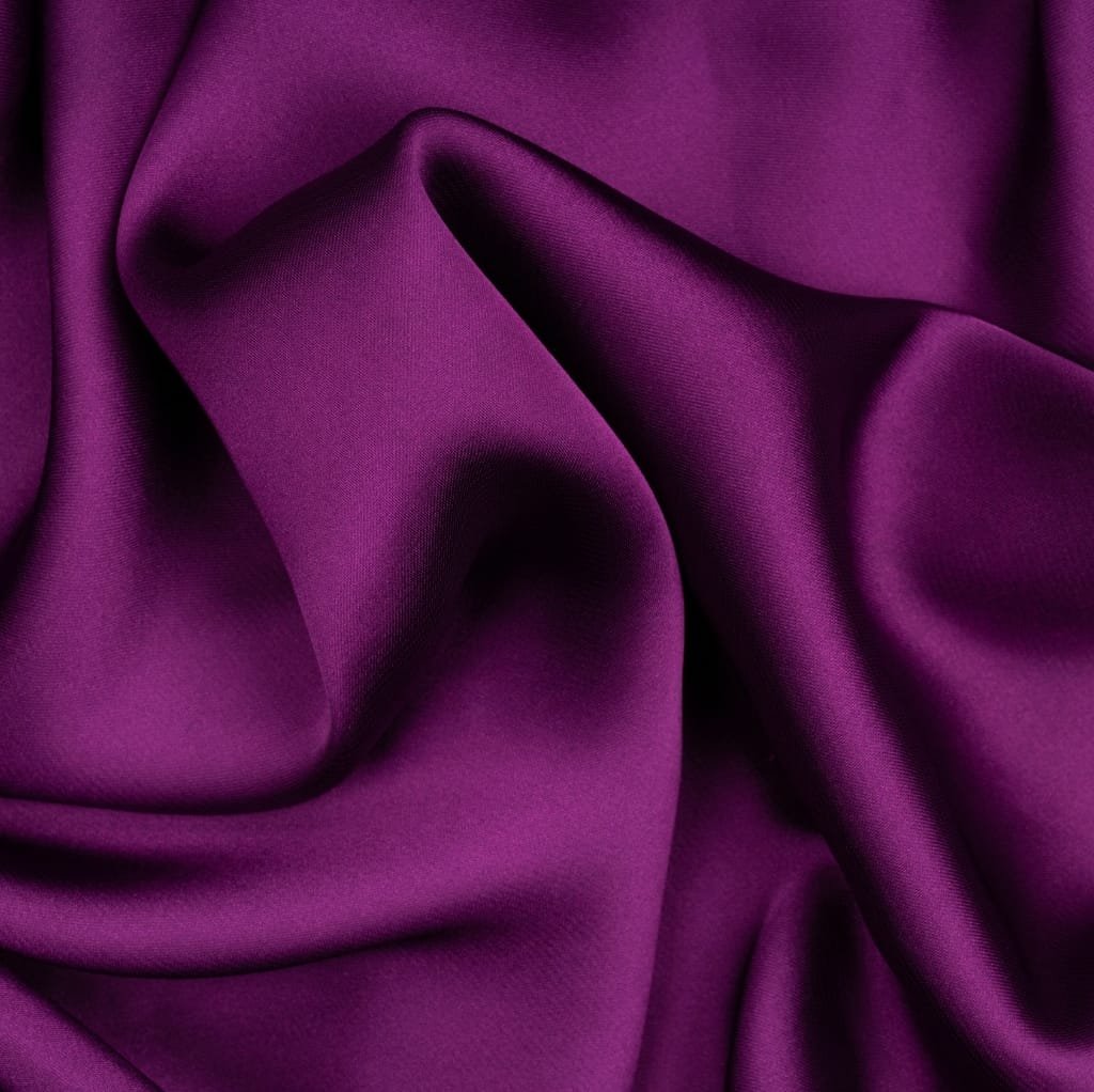 A close-up image of rich purple satin fabric with soft folds and a smooth, shiny surface.