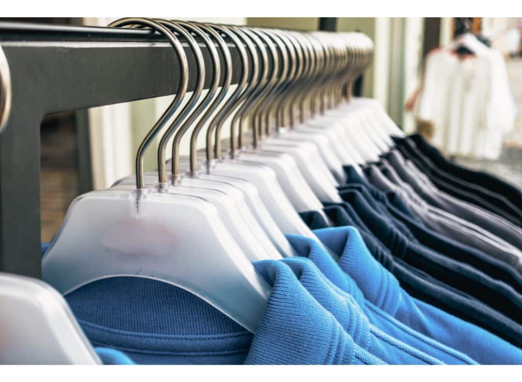 A row of polo shirts in various colors hanging on a rack at a clothing store.