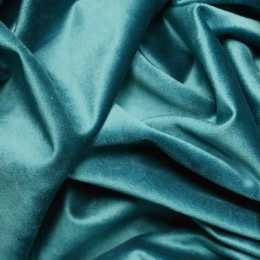 Close-up of deep teal rayon velvet fabric with a smooth, shiny, and plush surface.
