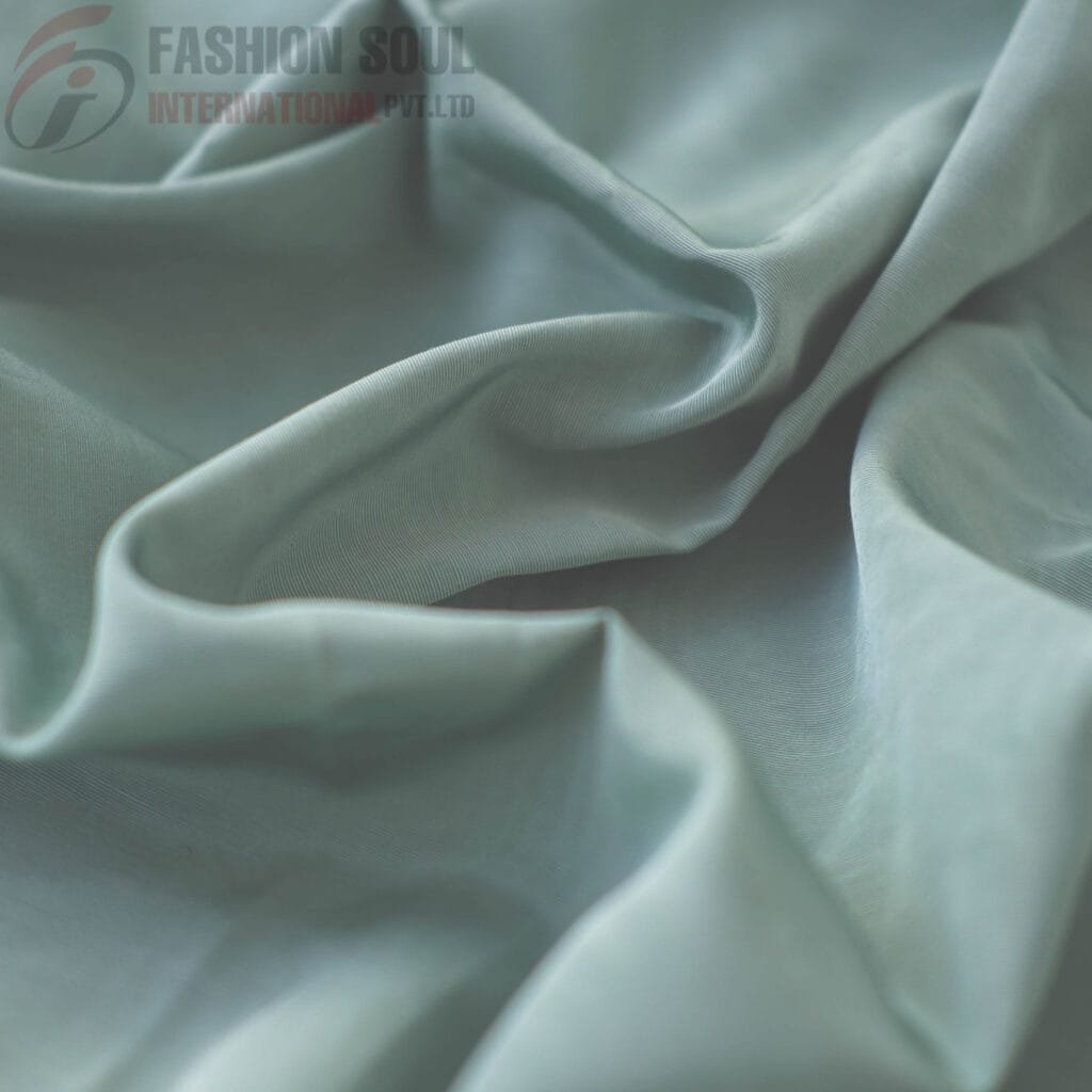 Soft, smooth, light-colored fabric with gentle folds and a slightly shiny surface.