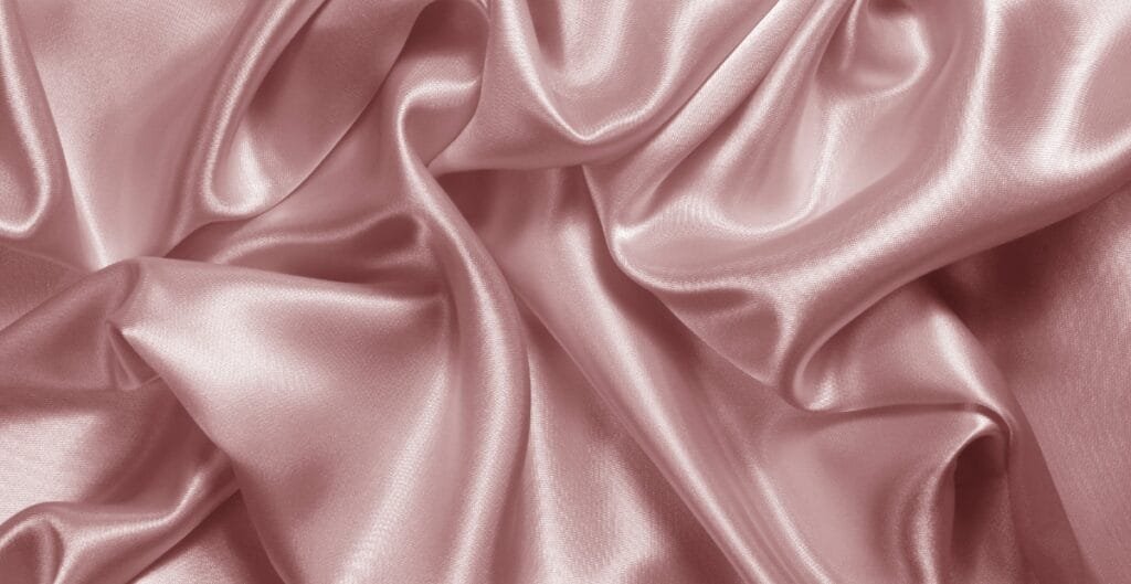 Smooth, shiny draped pink satin spandex fabric with soft folds and sheen.