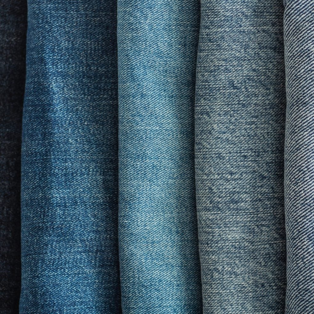 Close-up image of denim chambray fabric showing various shades of blue and detailed weave patterns.