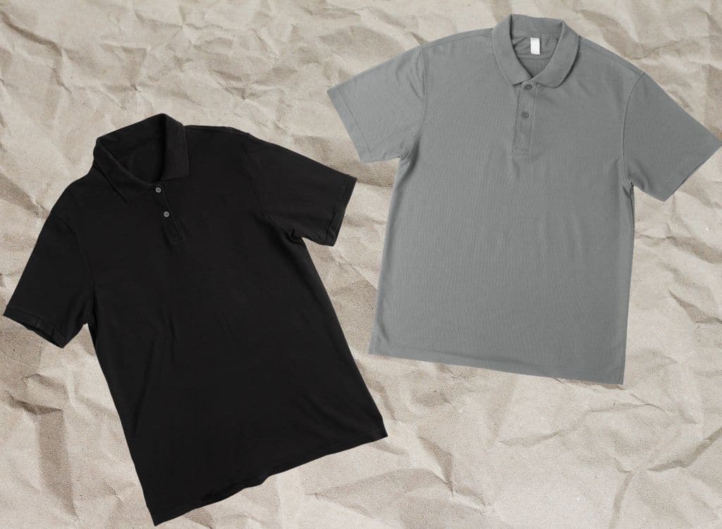 Two plain polo shirts, one black and one gray, spread out on a crumpled beige paper background.