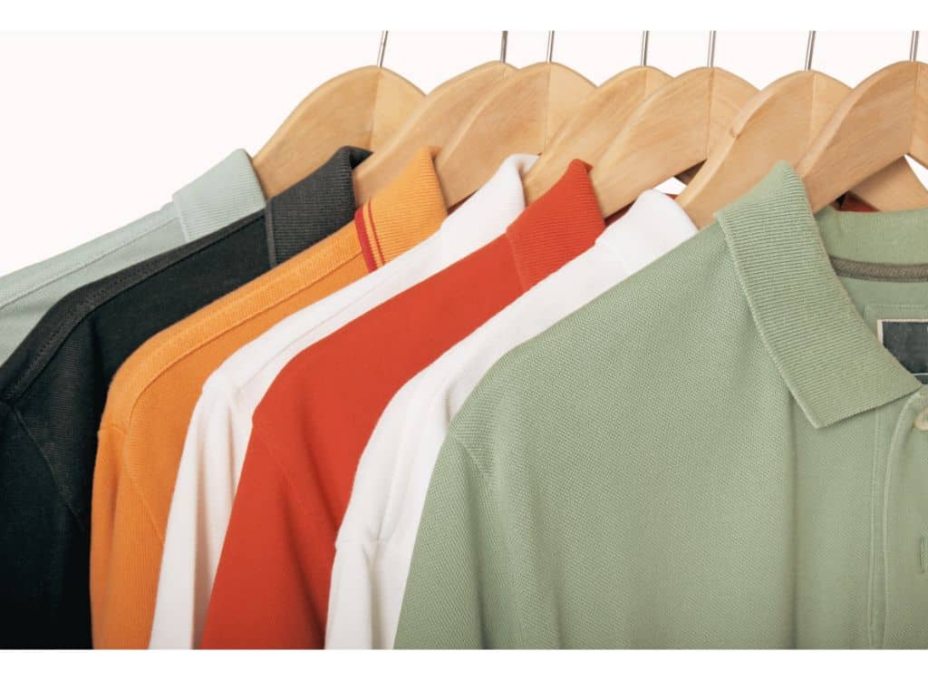 A variety of colorful customized polo shirts neatly arranged on wooden hangers.
