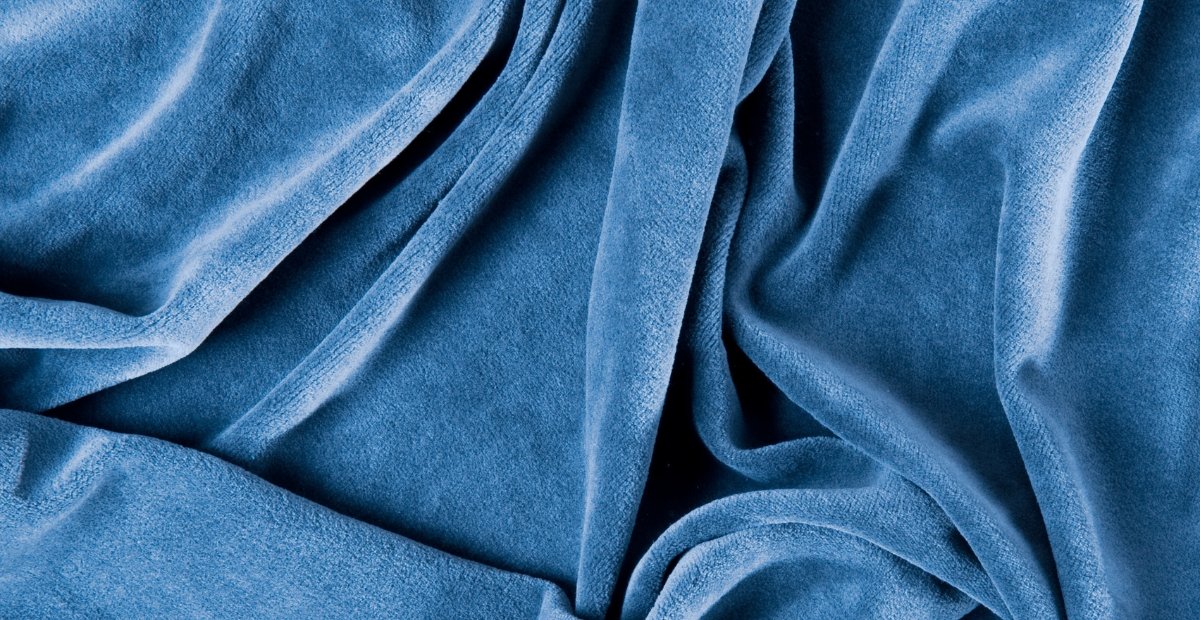 Close-up image of soft, blue velour fabric with gentle folds and a plush texture.
