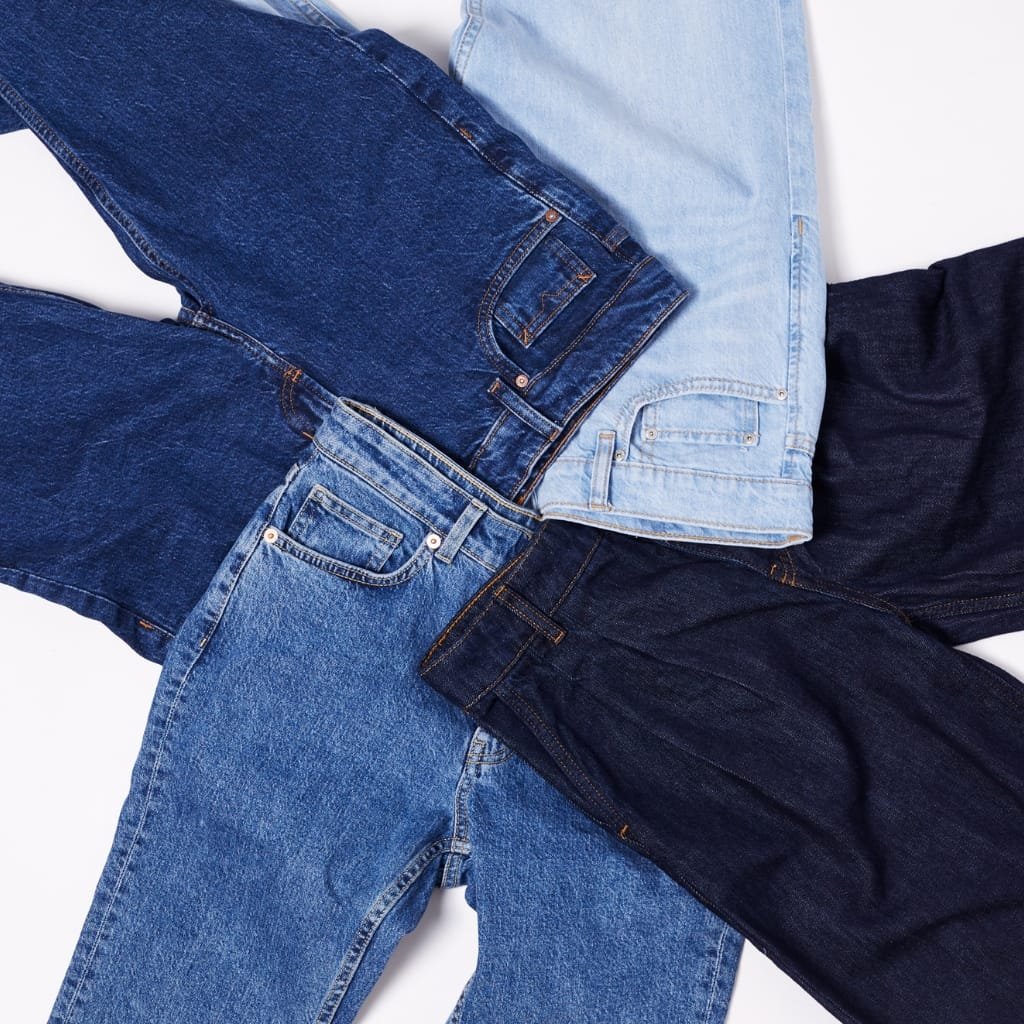 : A close-up photograph showcasing various denim fabric swatches in different shades of blue, layered overlapping each other.
