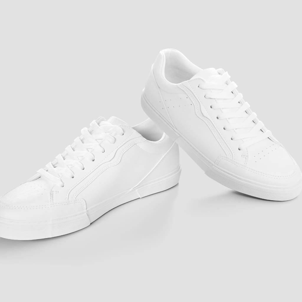 A pair of plain white sneakers with white laces and soles, positioned against a light gray background.