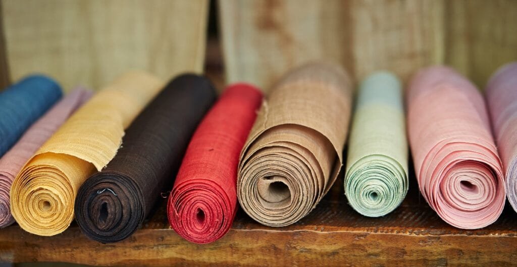 Rolled and unfolded colorful fabric pieces displayed on a wooden surface.