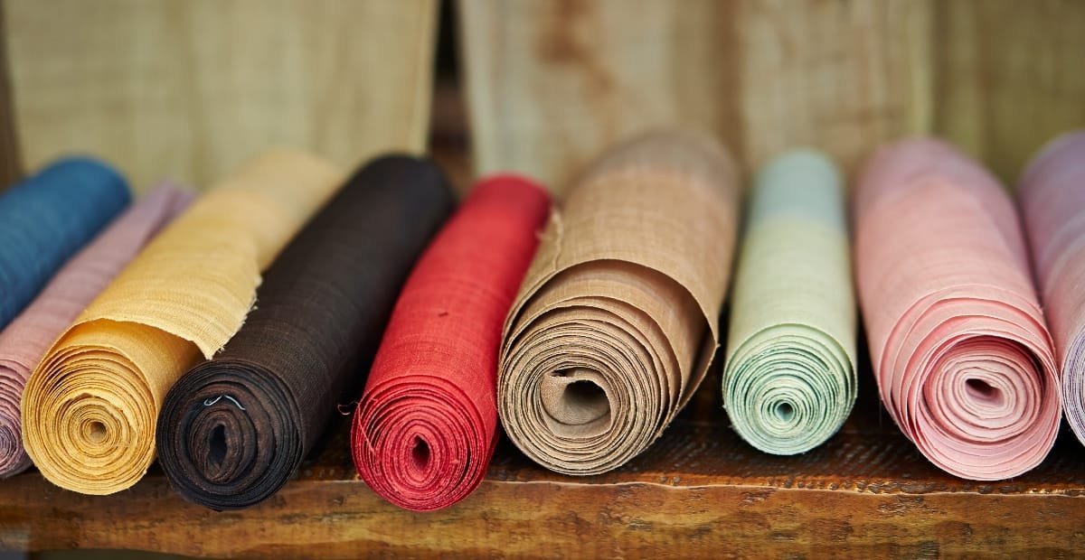 Rolled and unfolded colorful fabric pieces displayed on a wooden surface.