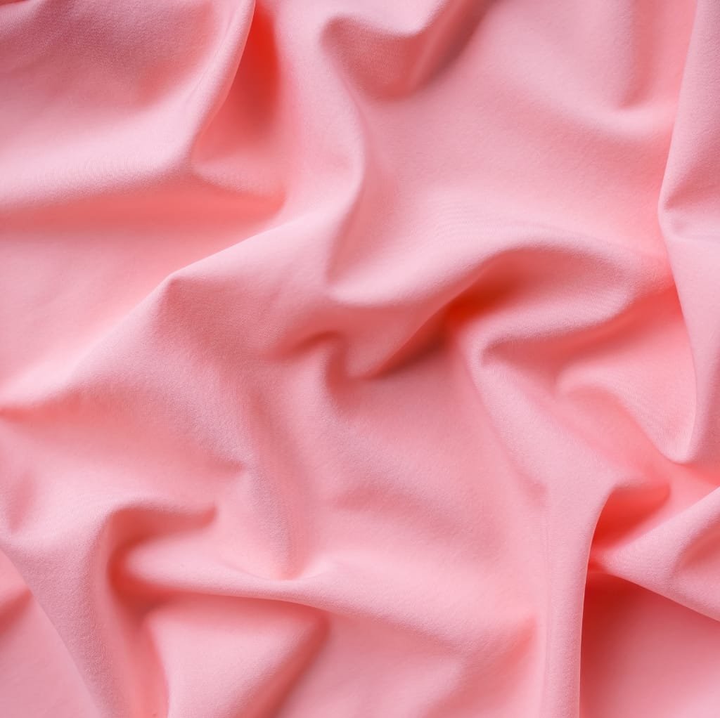 Close-up of soft, pink fabric with gentle folds and a smooth texture. premium cotton fabric