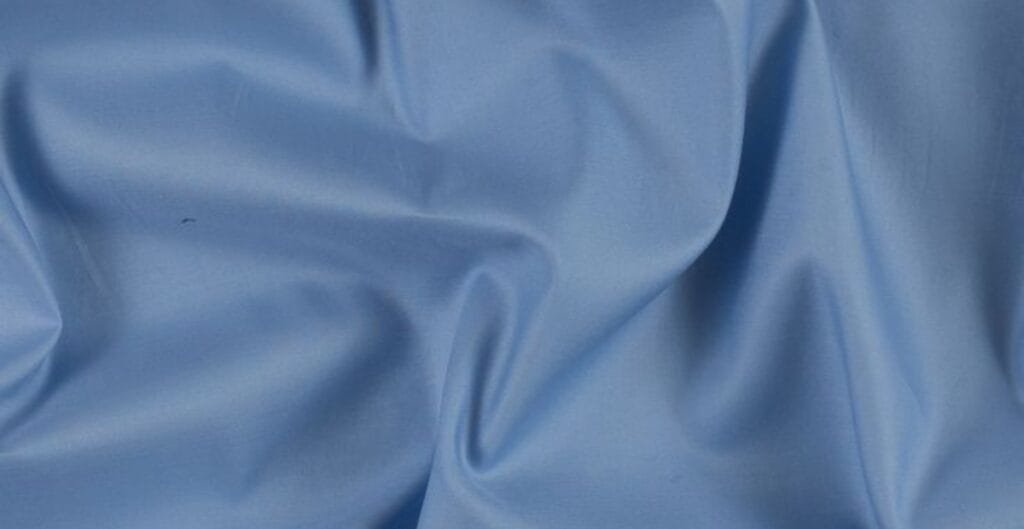 Close-up image of smooth, light blue Egyptian cotton fabric with gentle folds.
