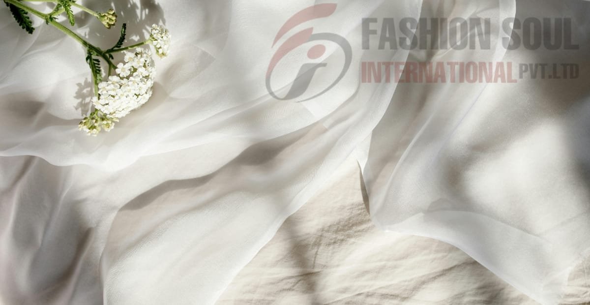 A close-up of white fabric with delicate white flowers and green stems resting on it, with a semi-transparent logo of "Fashion Soul International Pvt Ltd" in the background.
