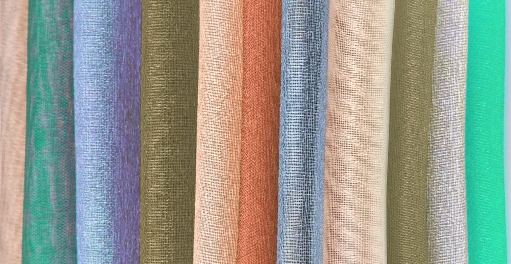 Close-up image of multiple rolls of nylon organza fabric in various colors, showcasing the sheer and lightweight texture.