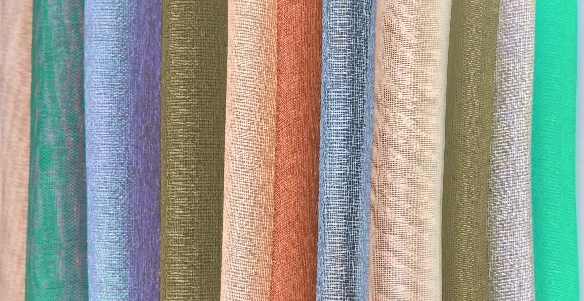 Close-up image of multiple rolls of nylon organza fabric in various colors, showcasing the sheer and lightweight texture.