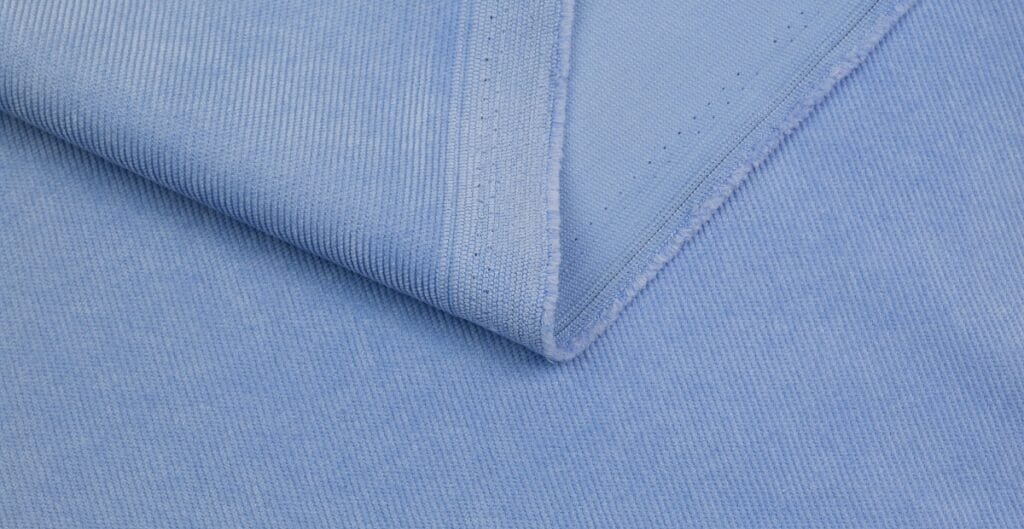 Close-up image of light blue corduroy fabric with distinct ridges and texture.