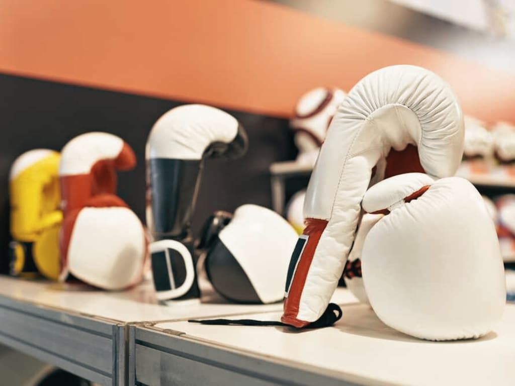 A display of various boxing gloves on a showroom shelf, showcasing different styles and colors.
