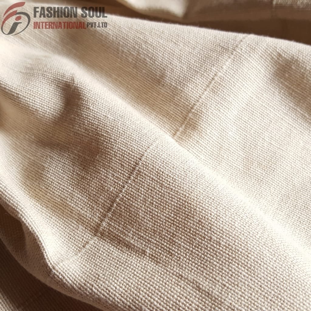Close-up of beige woven fabric with visible texture and stitching, showing detailed fabric weave and seam.