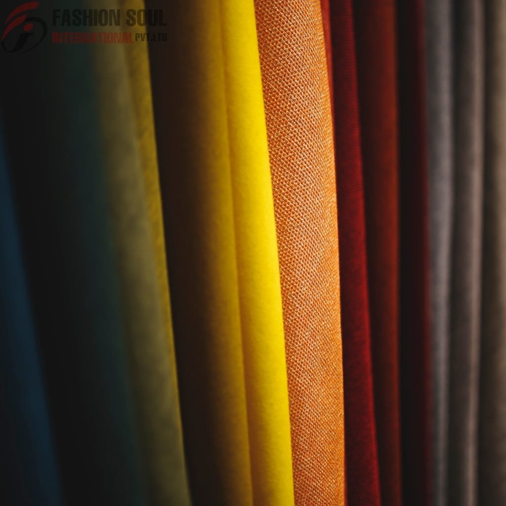 A close-up of vertically arranged fabric rolls in various colors, including yellow, orange, red, and dark shades, showing texture and pattern differences.