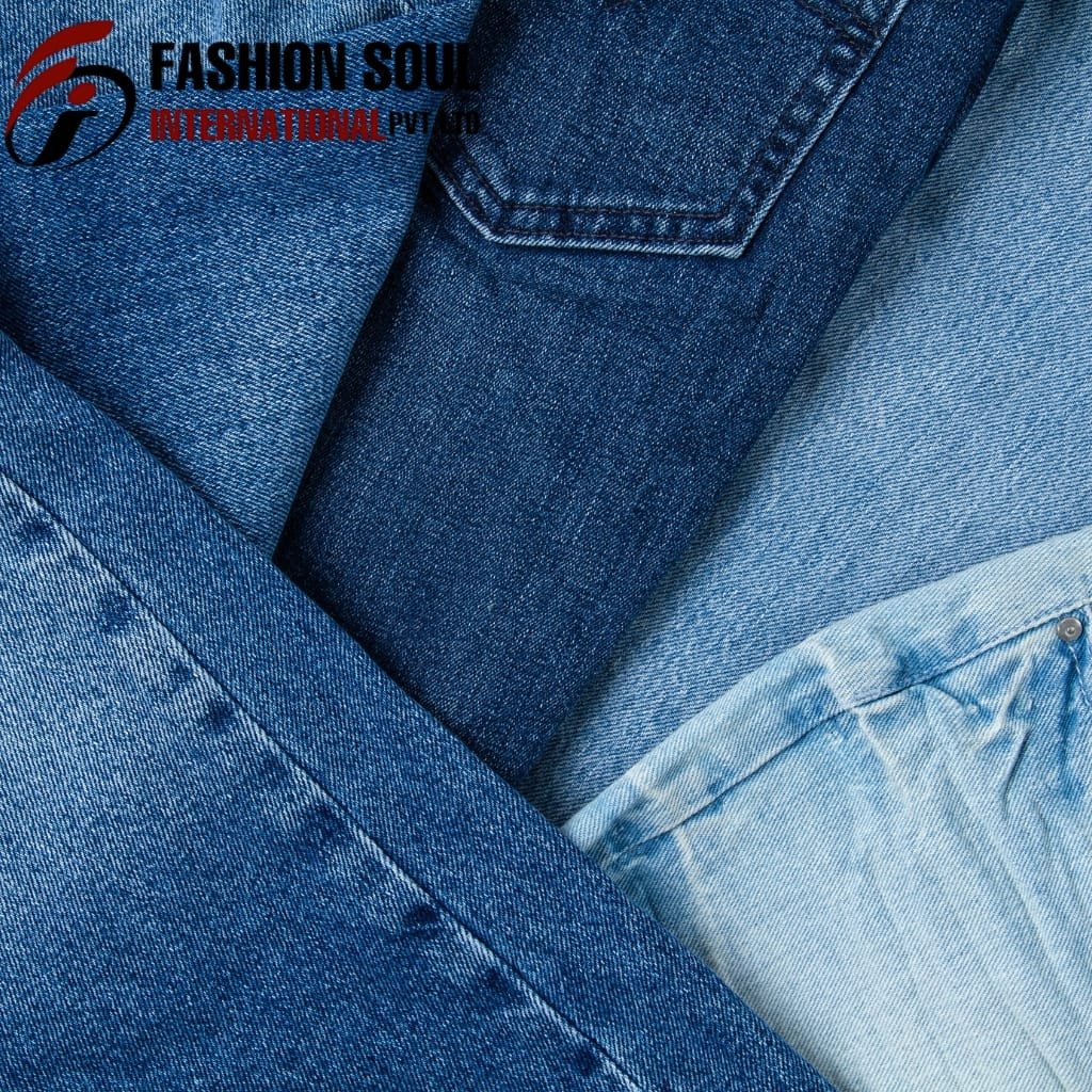 A close-up view of overlapping denim jeans in various shades of blue, highlighting the textures and stitching details.