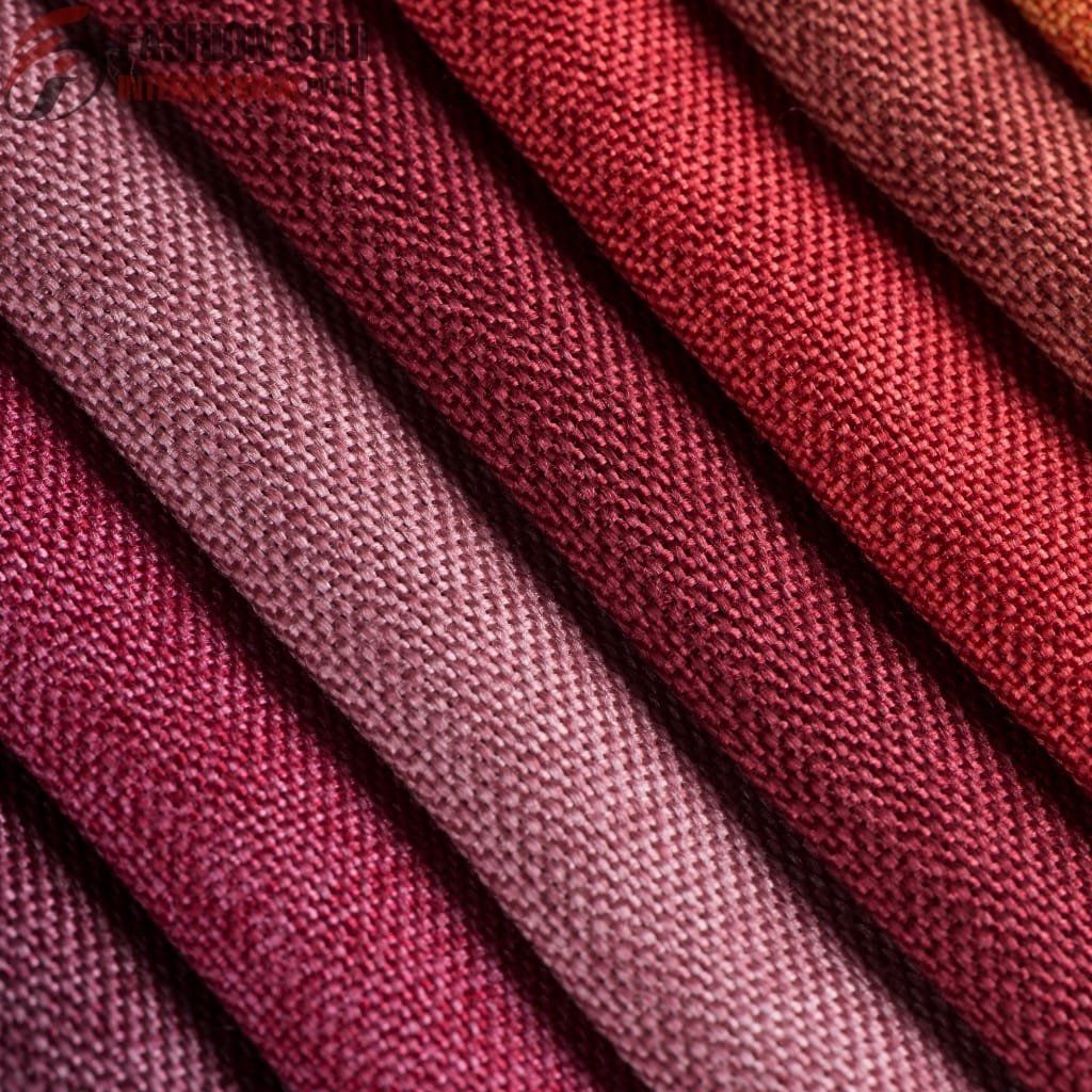 A close-up of multiple fabric swatches in various shades of pink and red, showcasing tightly woven textures and patterns.