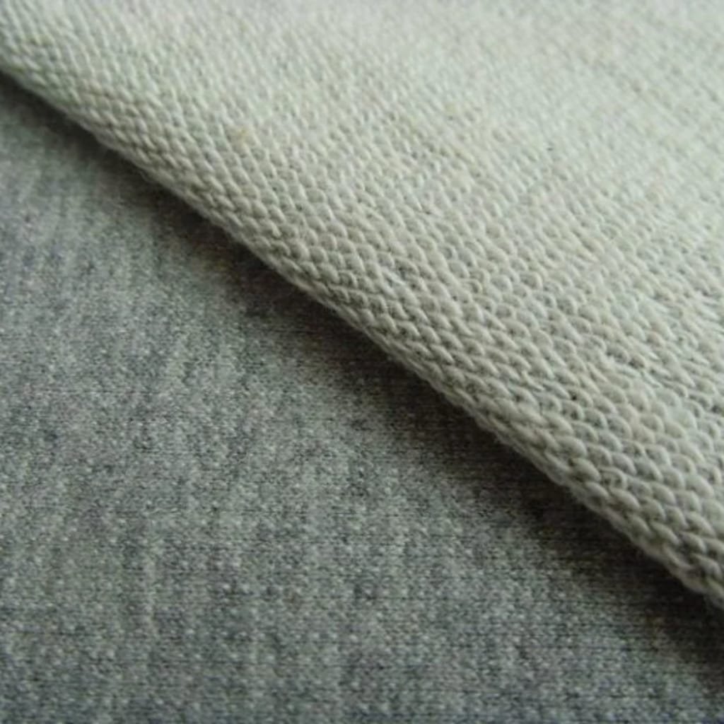 Close-up of a textured beige fabric laid over a rough gray surface.
