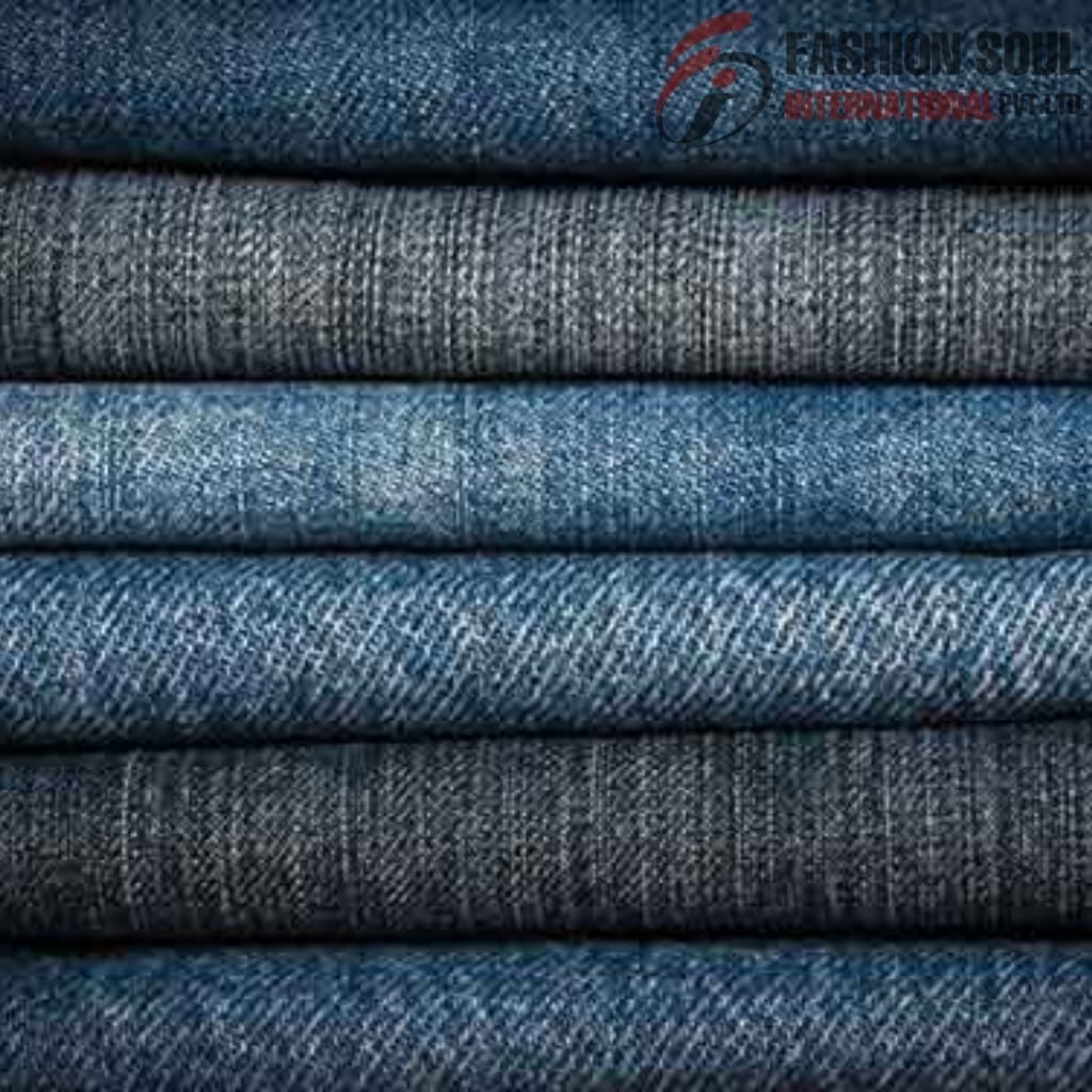 Stack of folded denim fabrics in varying shades of blue and gray, with a visible watermark in the top right corner.