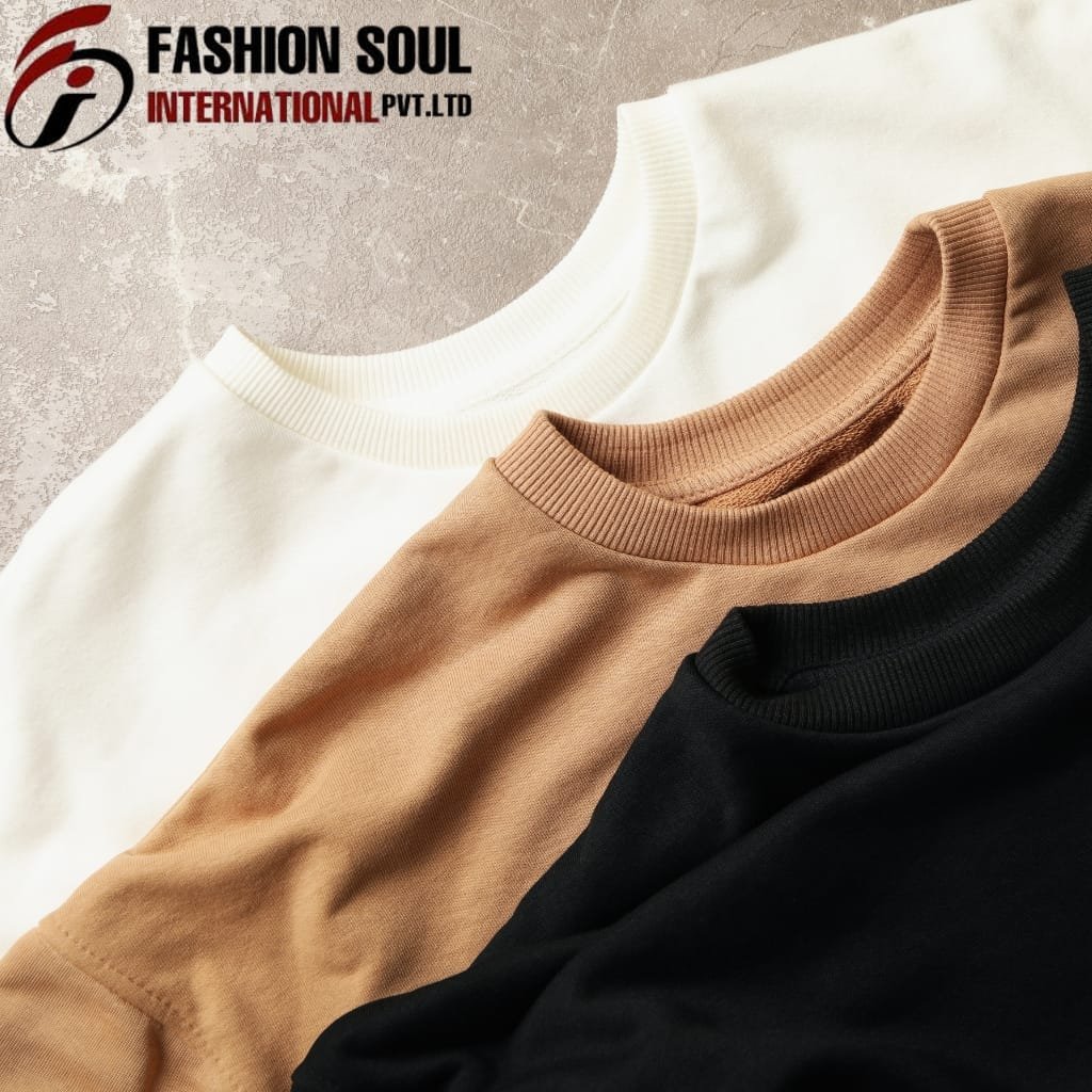 Close-up of three folded sweatshirts in white, brown, and black, layered on a textured surface with the "Fashion Soul International Pvt Ltd" logo in the top left corner.