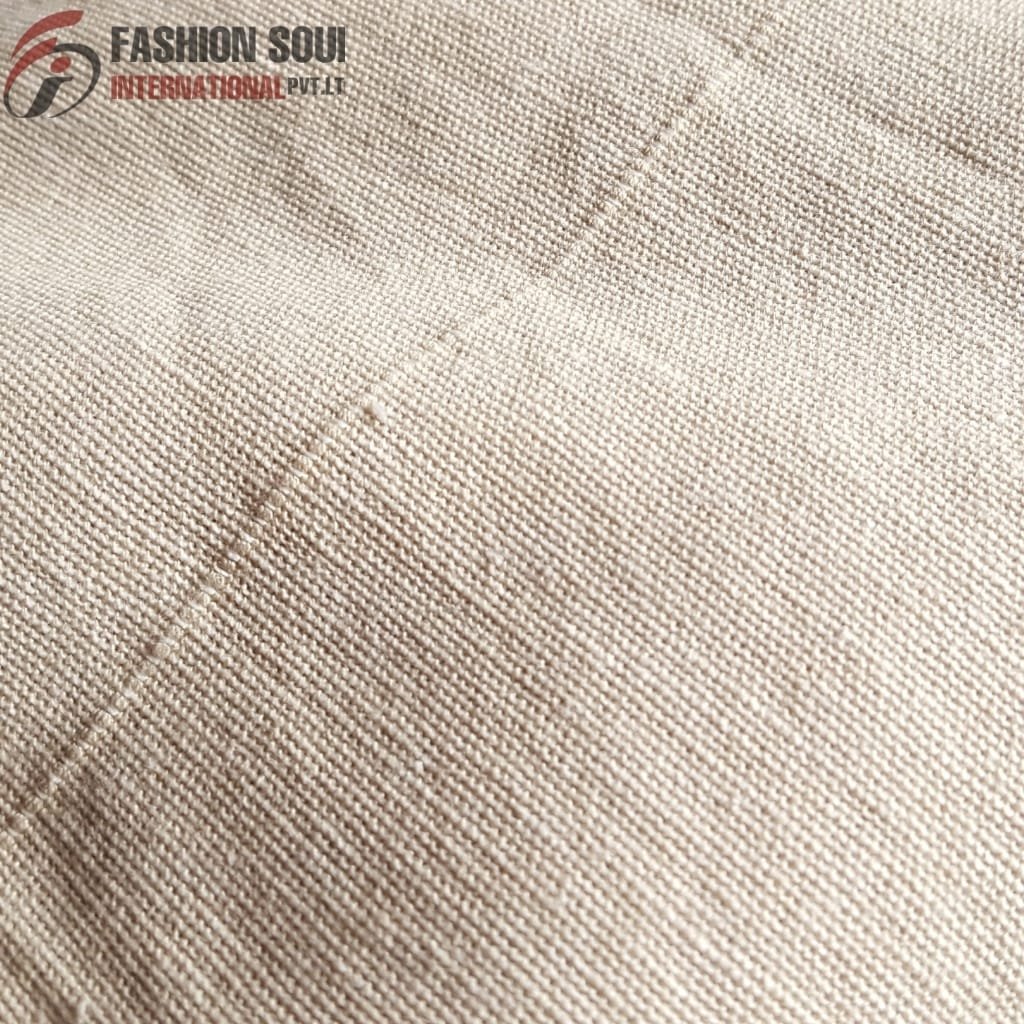 Close-up of a smooth, beige fabric with a tightly woven texture, featuring a subtle diagonal seam stitch, with the "Fashion Soul International Pvt. Ltd" logo in the top left corner.