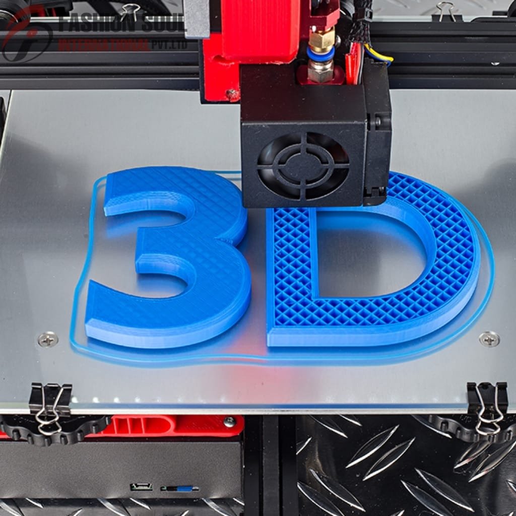 A 3D printer in the process of printing a large blue "3D" letters with a lattice pattern, positioned on the printer's print bed. The print head is actively extruding filament onto the letters.