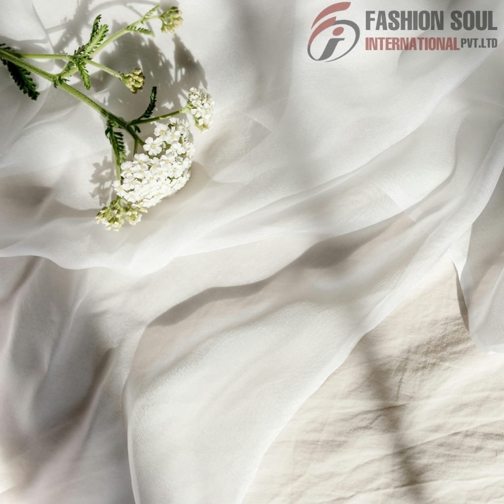 Light, flowing white fabric with a small branch of white flowers resting on it, and the "Fashion Soul International Pvt. Ltd." logo in the upper right corner.