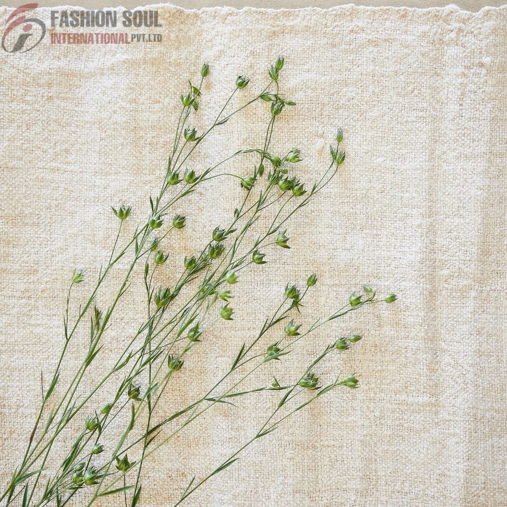 Close-up of delicate green plant stems with small buds, laid on a textured beige fabric background.