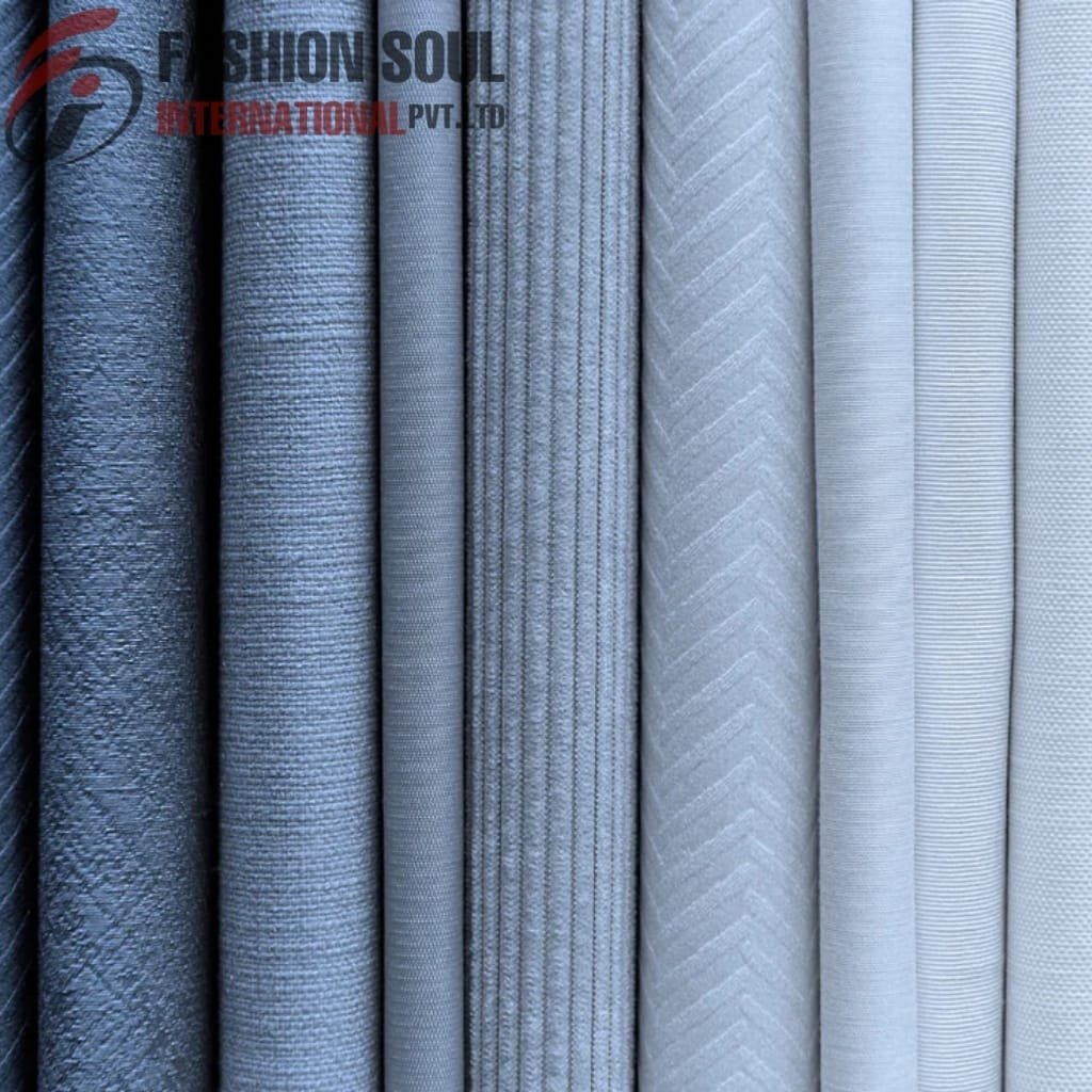A row of eight neatly folded fabrics in shades of blue and grey, featuring various textures and patterns, with a watermark in the upper left corner reading 
