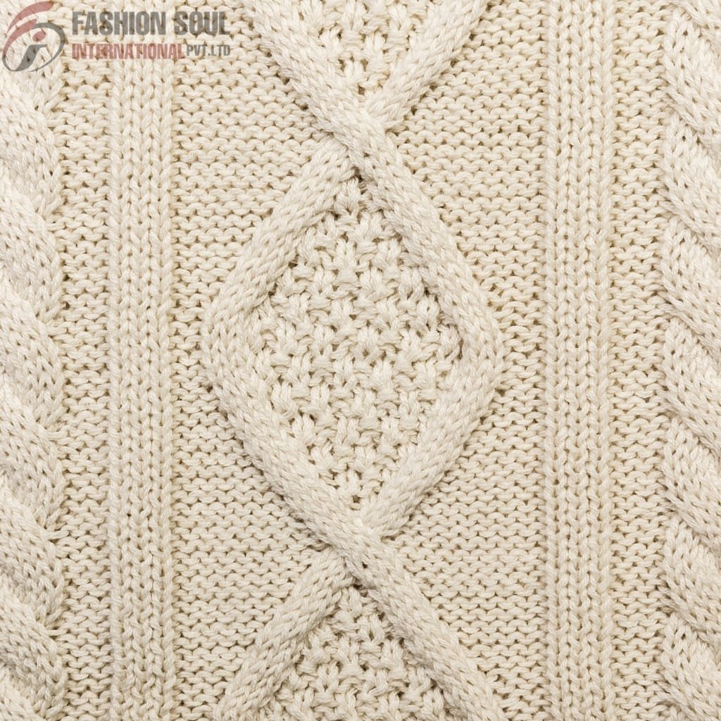 A close-up image of a knitted fabric pattern featuring a diamond-shaped cable design with braided edges, made of thick cream-colored yarn.